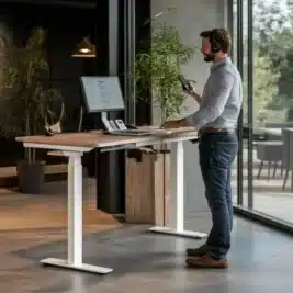 Homme debout utilisant un bureau assis-debout électrique blanc perle, L140 cm, avec deux moteurs, dans un espace moderne.