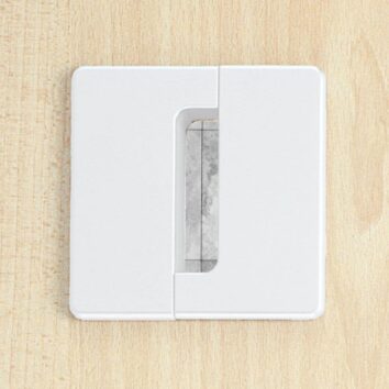 Obturateur passe-câbles carré blanc installé sur une surface en bois clair, avec un design moderne et épuré.